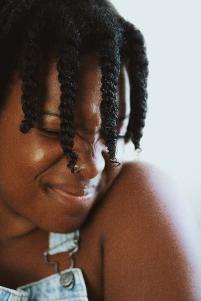 black girl smiling into her shoulder