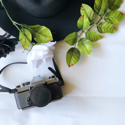 black film camera with hat and greenery