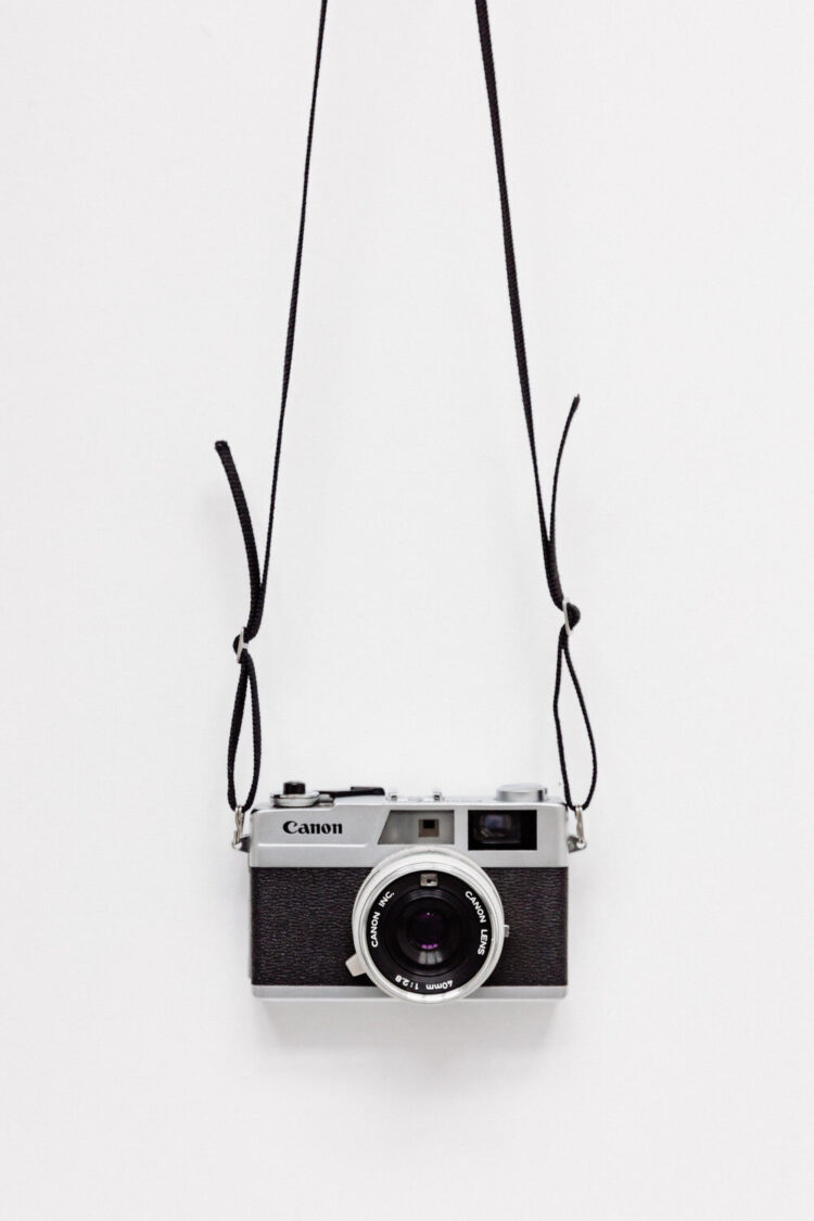 black film camera hanging on gray wall