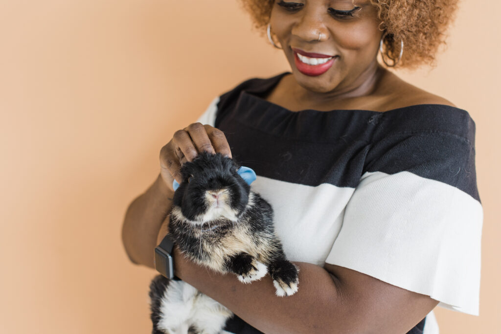 Black woman holding a tri-color bunny rabbit wearing a bow tie